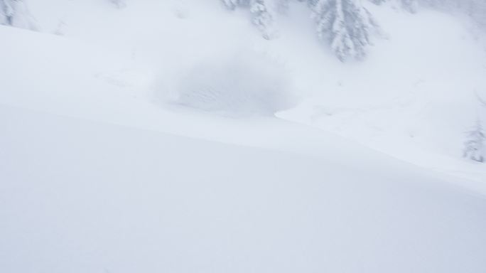 免费滑雪者从悬崖上跳下，在壮丽的冰冻景色中降落在刚落下的雪上