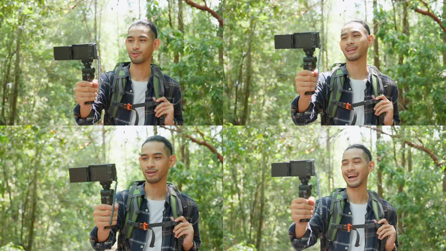 亚洲英俊男背包客vlogger独自在森林中旅行。吸引人的男子旅行者使用手机录制视频博客，在假期旅行中