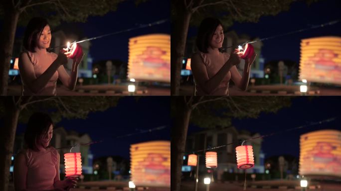 亚裔中国妇女在纸灯笼上点燃蜡烛，庆祝中秋节。