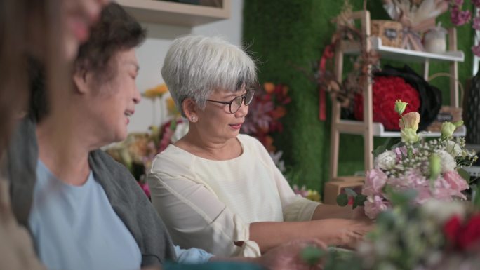 亚裔中国老年女性在花店向女花商学习插花