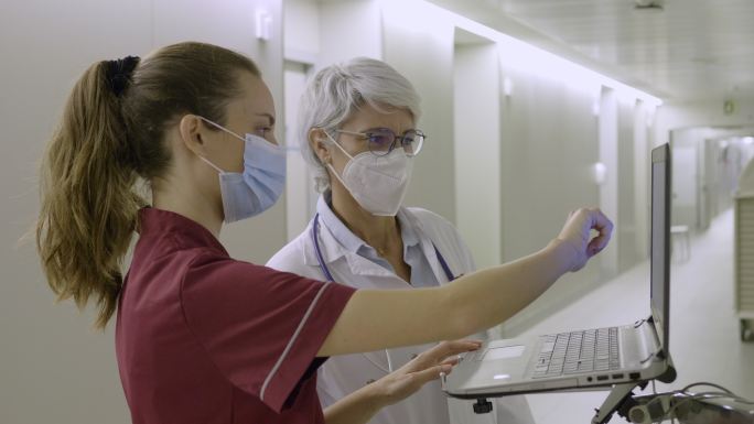 两名医生在医院走廊一起使用笔记本电脑