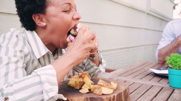 一名非洲裔美国中年妇女在餐厅吃汉堡
