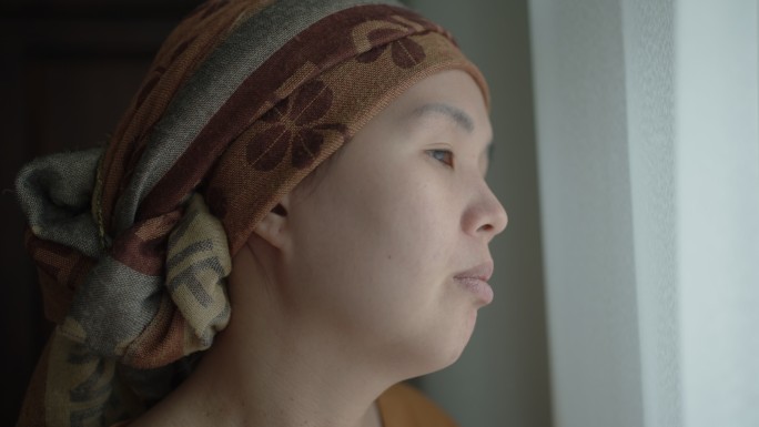 亚洲癌症女性肖像在窗口往外看的女人面无表