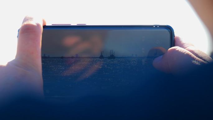 海边用手机拍摄开海的男人