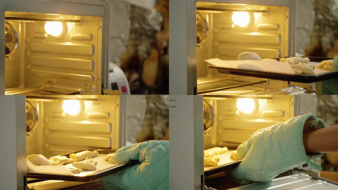 手拿烤箱手套将泡芙糕点托盘放入烤箱，准备在家烘烤。