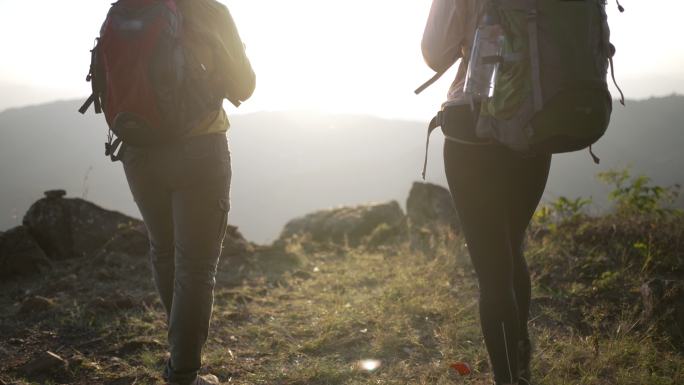 两个带着露营背包的女徒步旅行者徒步走到山顶