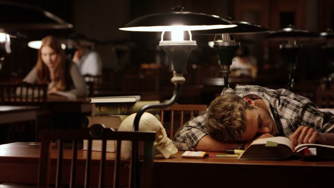 DS年轻男医学生在图书馆睡着了