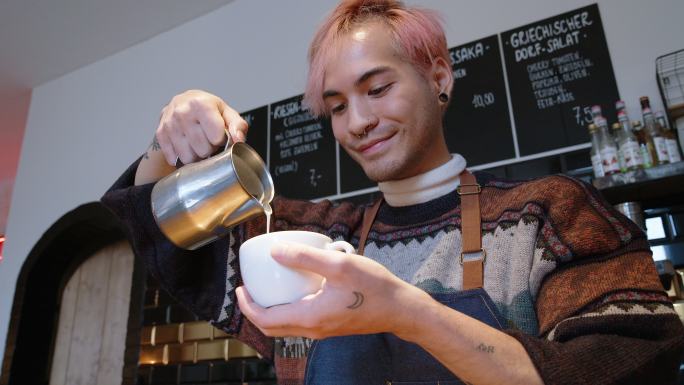 咖啡师用泡沫牛奶制作拿铁艺术