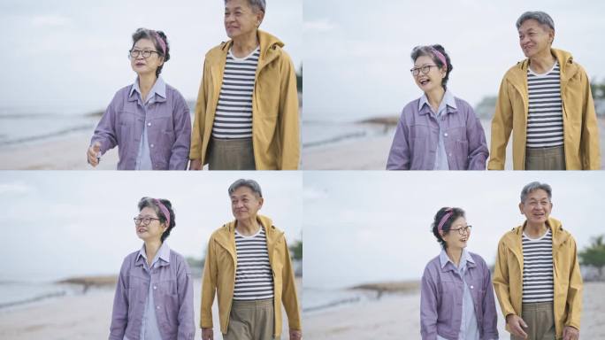 亚洲华人老年夫妇在海滩上穿着暖和的衣服看着别处