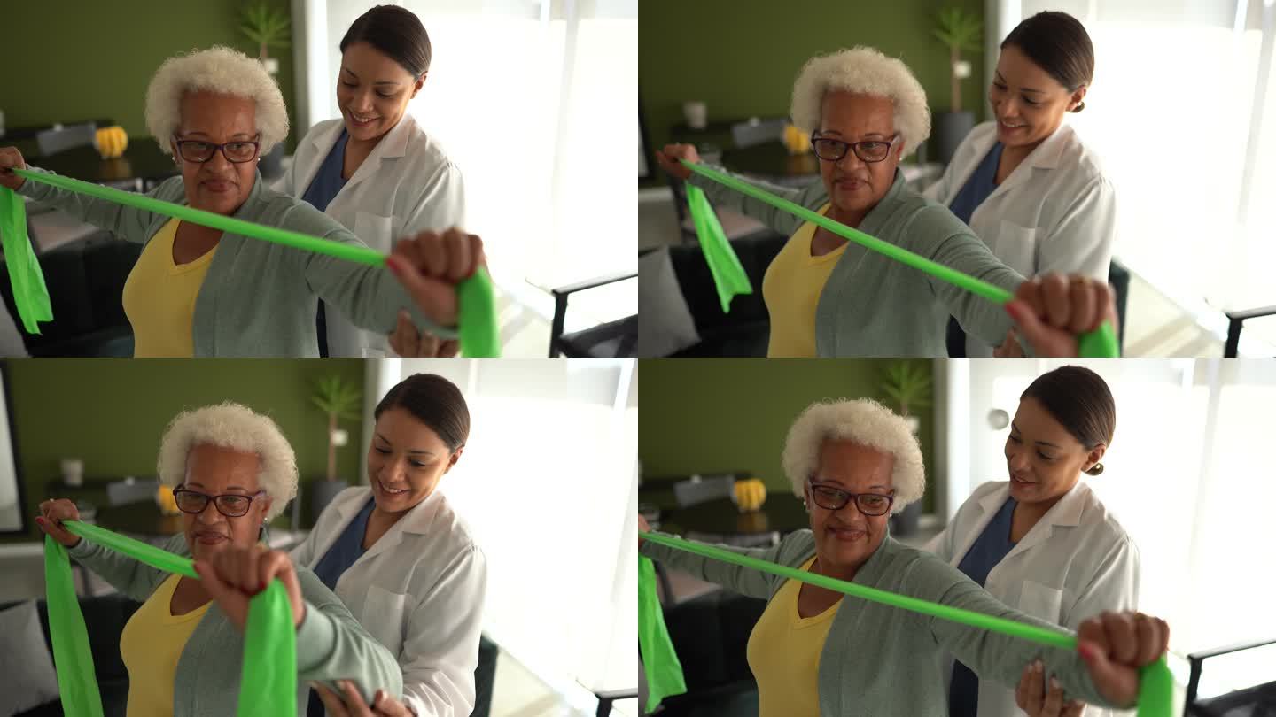 物理治疗师帮助老年妇女在家中使用阻力带进行练习
