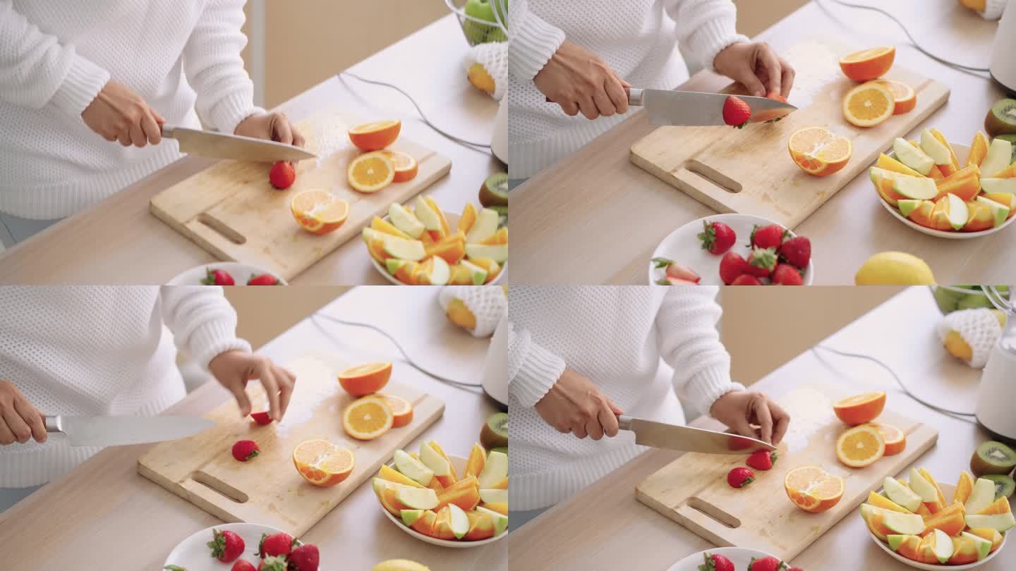 准备自制草莓、苹果、橘子和猕猴桃冰沙，由高级女士手将水果切成小块，高角度侧视图