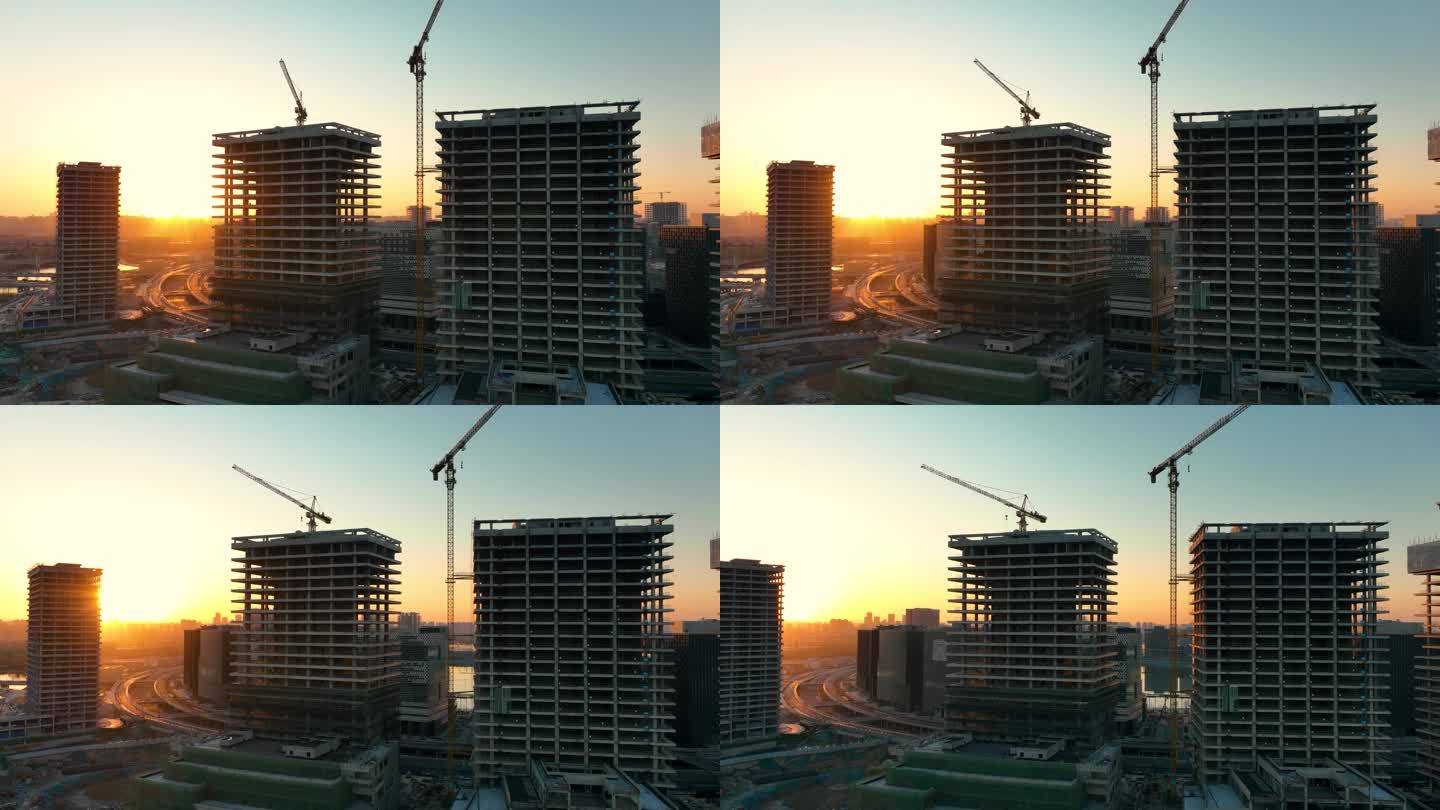 日落时建筑工地上的建筑起重机鸟瞰图