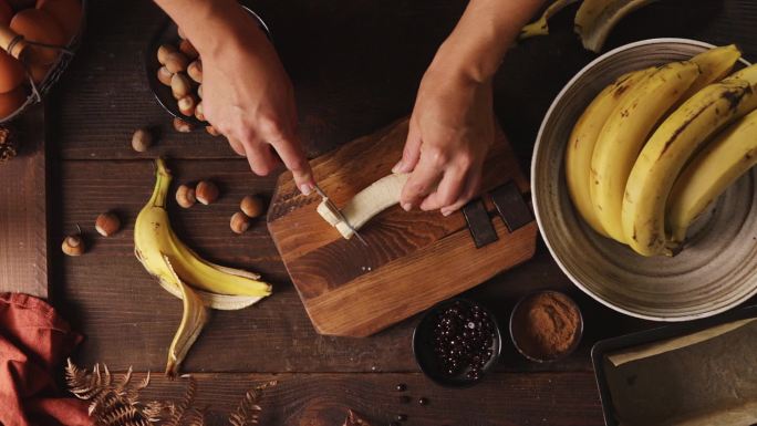 一个女人在厨房切香蕉的手的特写镜头