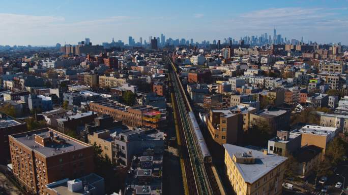 日落时分，一列火车正穿过纽约布鲁克林的居民区。背景是曼哈顿的远景。无人机视频，摄像机向前移动，跟踪列
