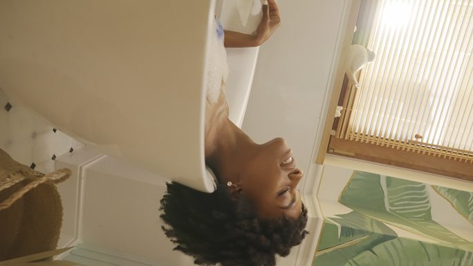 美丽的非洲裔女性在现代浴室中与音乐重新组合