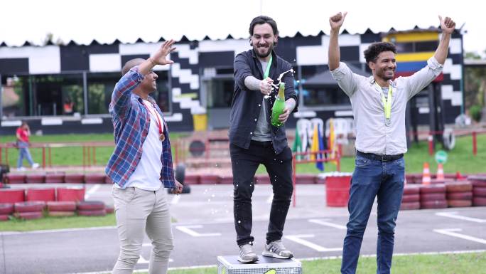 快乐的朋友们在围棋车赛道的领奖台上，用香槟和击掌庆祝他们的胜利