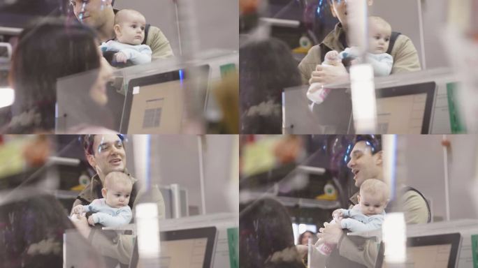收银员在超市收银台帮助一名男子带婴儿
