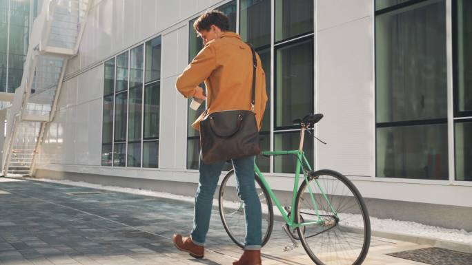 一个年轻人早上骑着自行车和一杯咖啡来上班