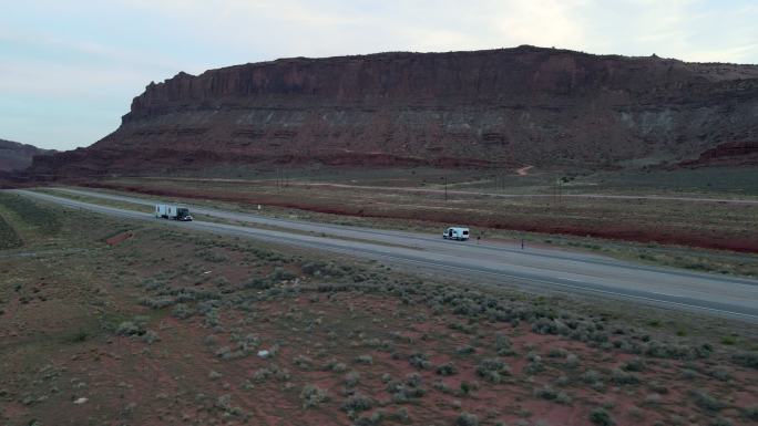 在犹他州西南部摩押附近的红石砂岩地区沙漠，一辆半卡车在四车道公路上疾驰