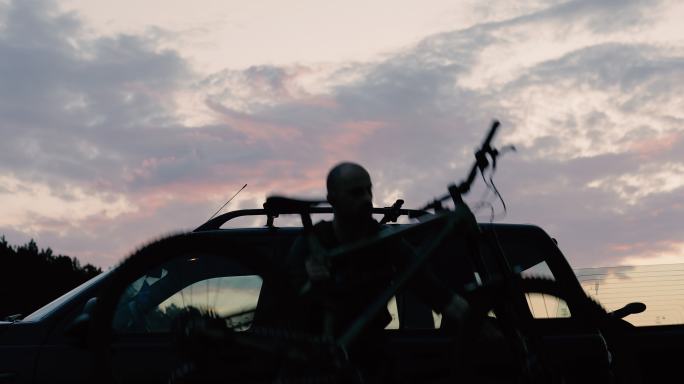 日落时，一名男子正把自行车挂在车顶支架上