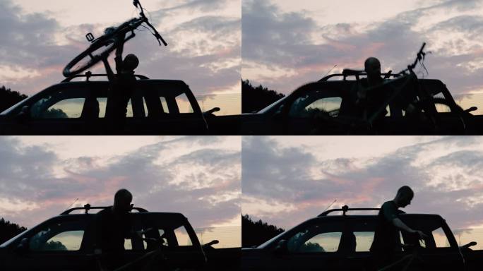 日落时，一名男子正把自行车挂在车顶支架上