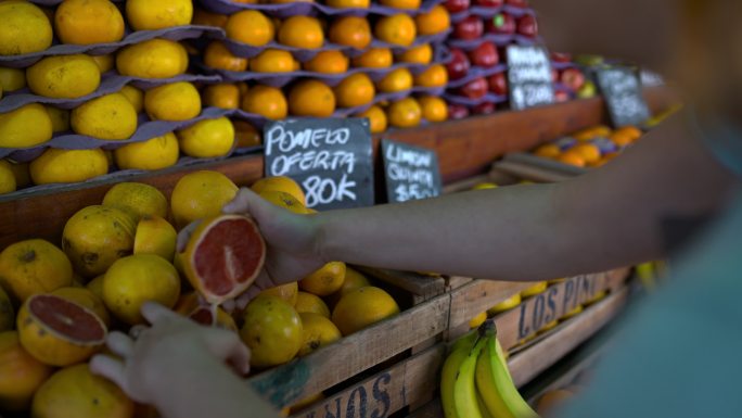 一位面目全非的女售货员正在农贸市场的摊位上布置水果展示
