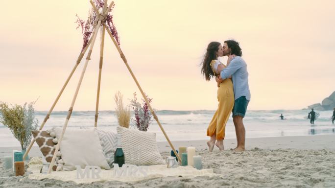 一对幸福的年轻夫妇求婚后在海滩上拥抱拥抱。一对恋爱中的男女，亲吻并庆祝他们的订婚