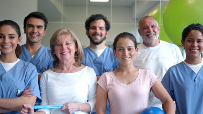 一组患者和不同的治疗师，在物理康复中心面对镜头微笑