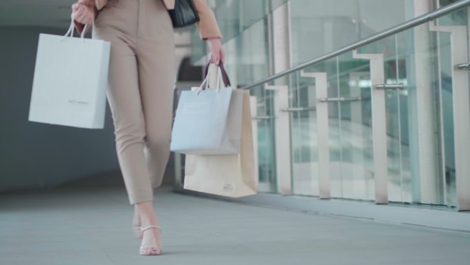 一个亚洲女人在商场里拿着购物袋走路
