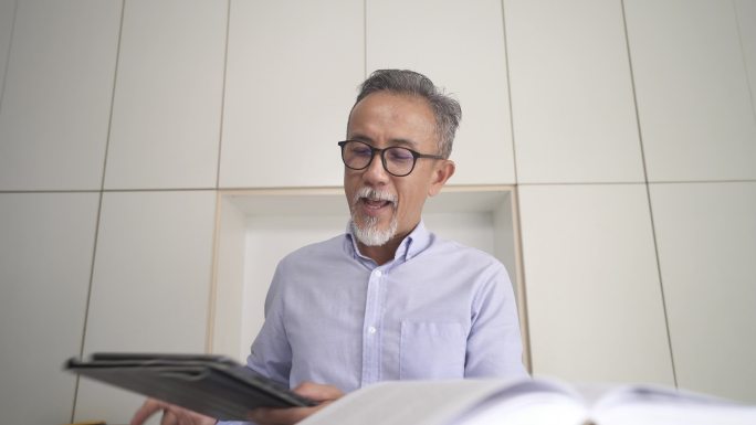 亚裔中国资深教授、导师、教师在家里使用笔记本电脑为成年学生提供在线课程