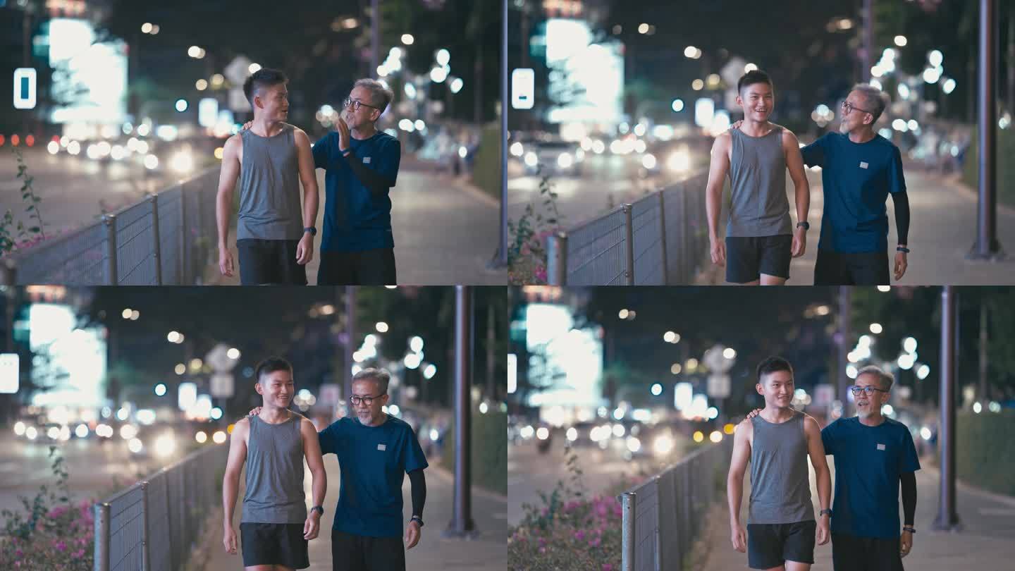 亚裔中国活跃的老人和他的儿子在一起跑步、锻炼后，晚上在城市里散步、聊天