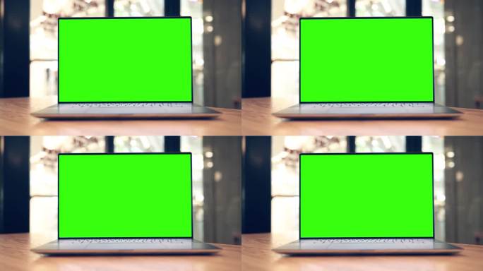 咖啡馆桌子上有空白绿色屏幕的笔记本电脑