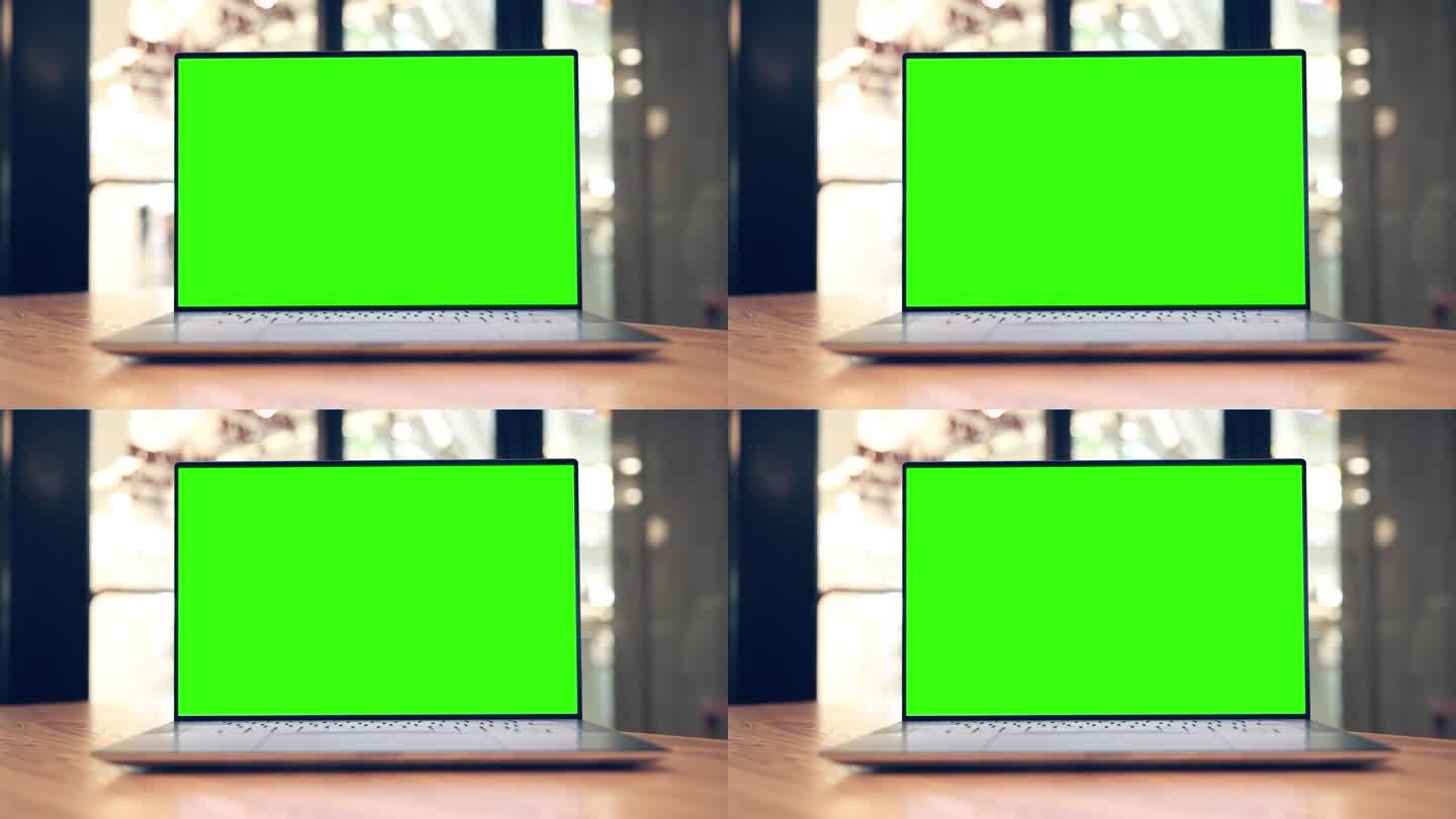咖啡馆桌子上有空白绿色屏幕的笔记本电脑