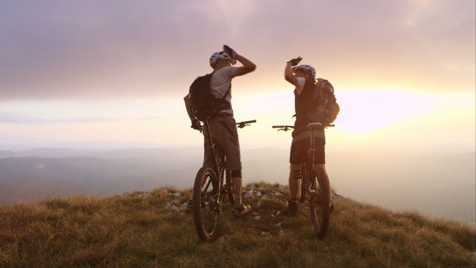 TS山地自行车手在日落时到达山顶并举手