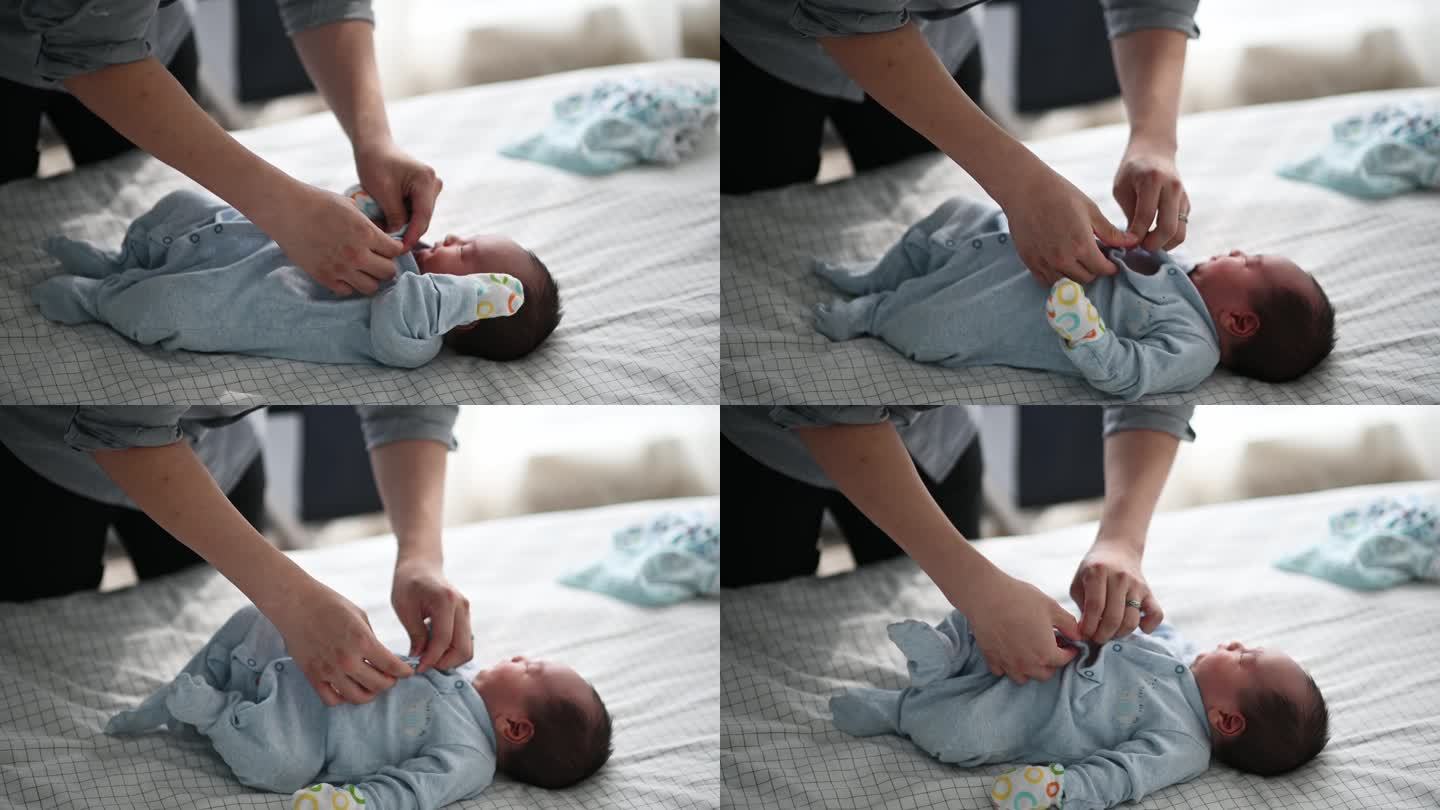 亚裔中国年轻父亲在床上为他的男婴扣扣子