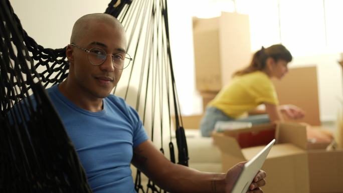 一个年轻人使用笔记本电脑和丈夫在家打包移动箱子的肖像