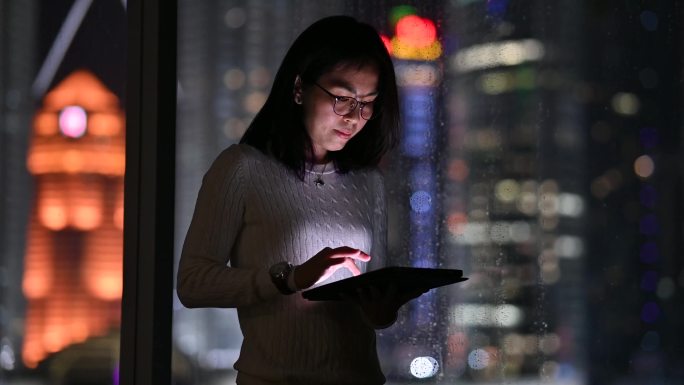 一位亚洲女商人晚上在数字平板电脑上在线工作