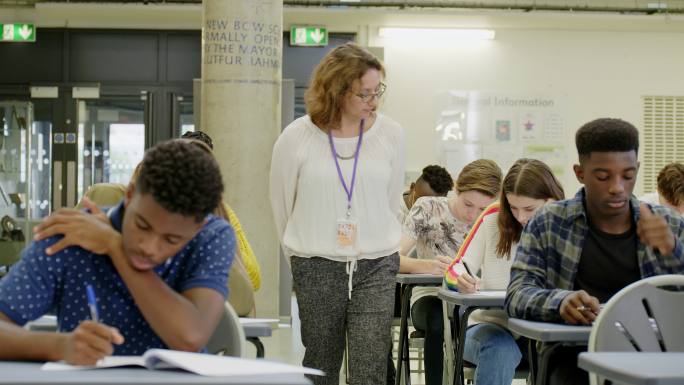 女初中教师，在教室的课桌上监督学生考试