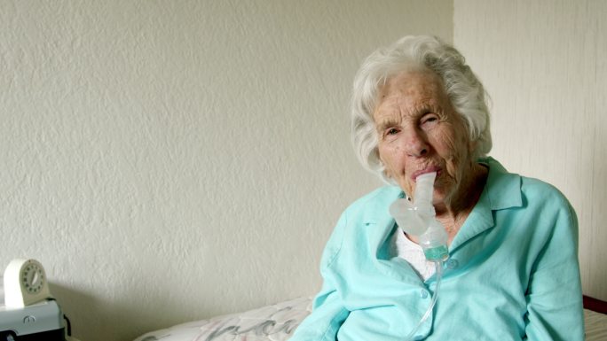 一名高加索女性在使用喷雾器吸入治疗哮喘的药物或打开肺部气道时，竖起大拇指