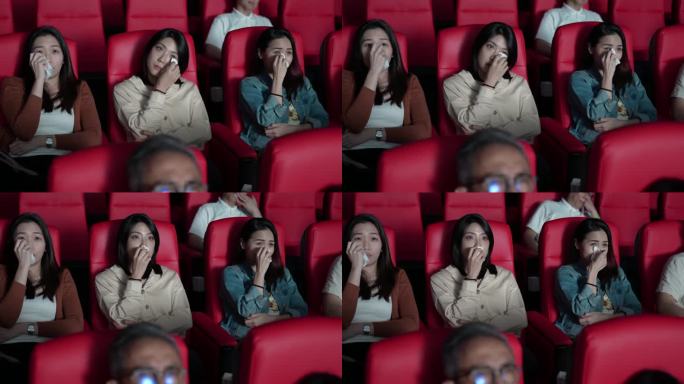 亚裔中国女性朋友在电影院里哭泣，看伤感的戏剧电影，电影院，用纸巾擦眼泪