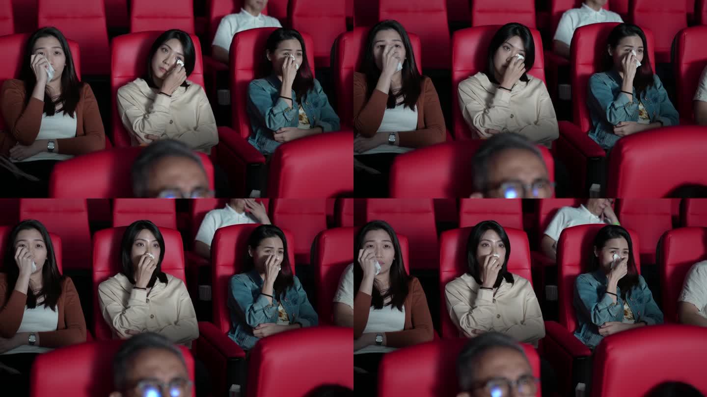 亚裔中国女性朋友在电影院里哭泣，看伤感的戏剧电影，电影院，用纸巾擦眼泪