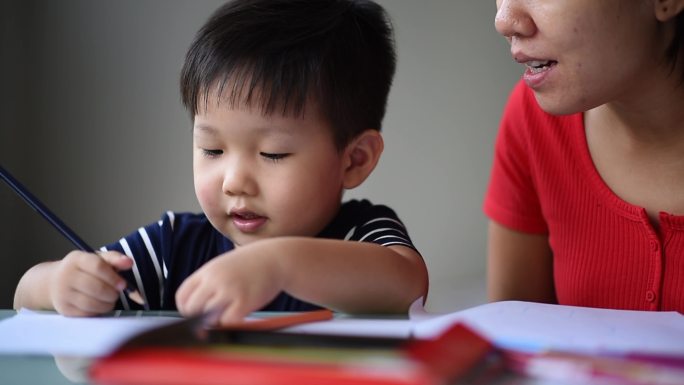 亚洲华人母亲在办公室教她可爱的小男孩绘画艺术