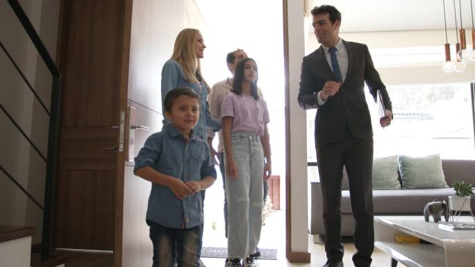 一个拉丁美洲家庭，带着两个孩子，一位房地产经纪人向他们展示了一处漂亮的房产，他们看起来都很兴奋
