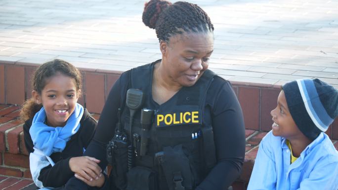 社区里的女警察和两个孩子坐在一起