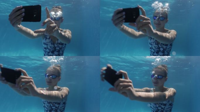 一个十几岁的女孩在游泳池的水下用智能手机自拍。