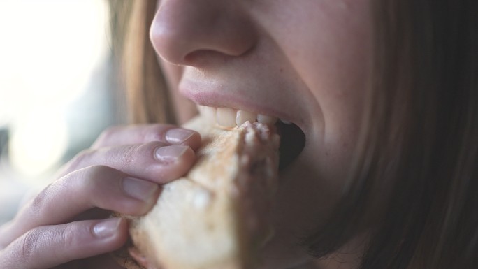 女性美女在慢动作视频中咀嚼令人愉快的吐司