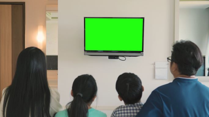 快乐的家庭坐在家里看色度键电视