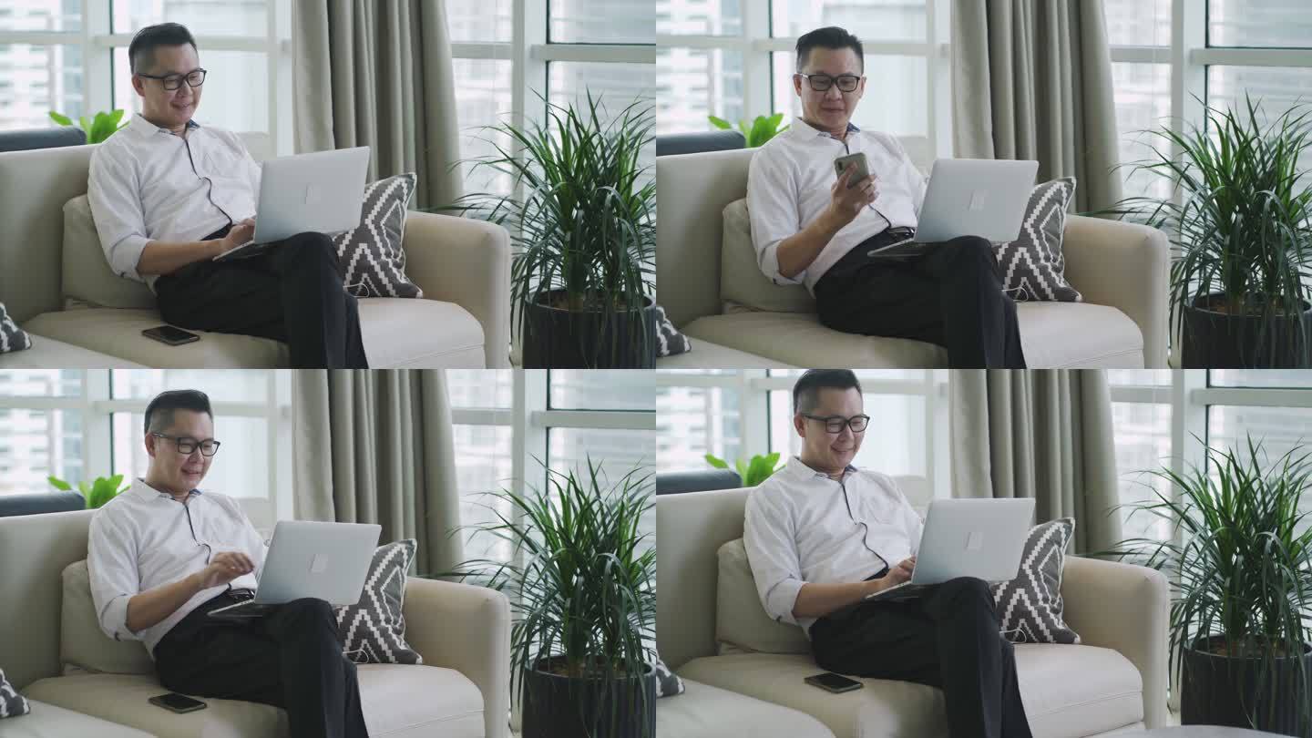 一位亚裔中国中年商人坐在商务休息室里，微笑着用笔记本电脑查看他的电话留言