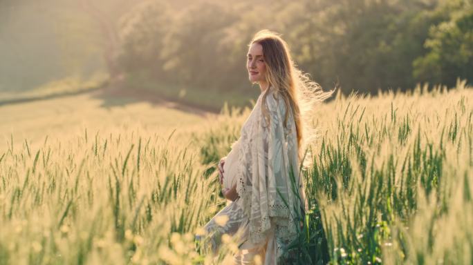 一位美丽的怀孕少女在乡村的田野里放松。快乐孕妇享受自然放松的产假