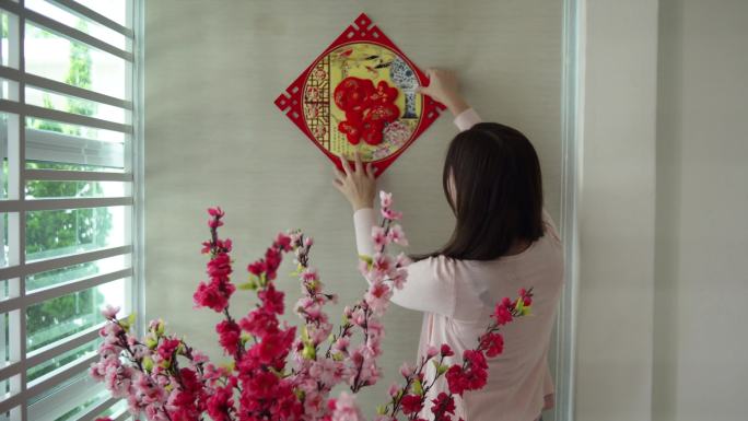 亚洲华人妇女在除夕夜用“财富”春联装饰她的房子